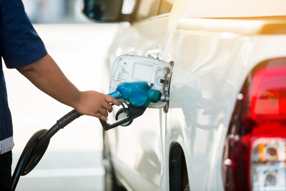 Hand refilling a white pickup truck with fuel at the gas station